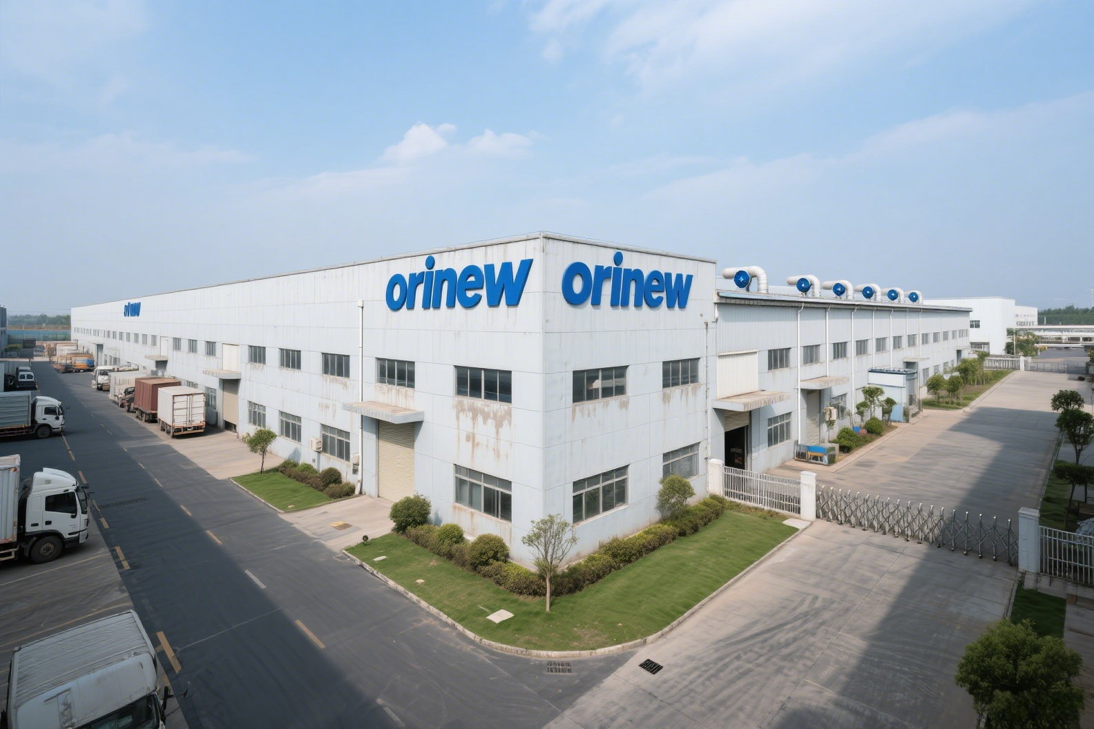 Large white factory building with the blue 'orinew' logo, loading docks, and trucks parked along a road nearby.