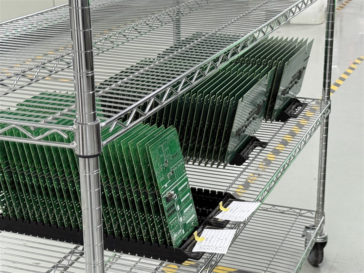 Representative factory photo of PCB panels held in racks before assembly