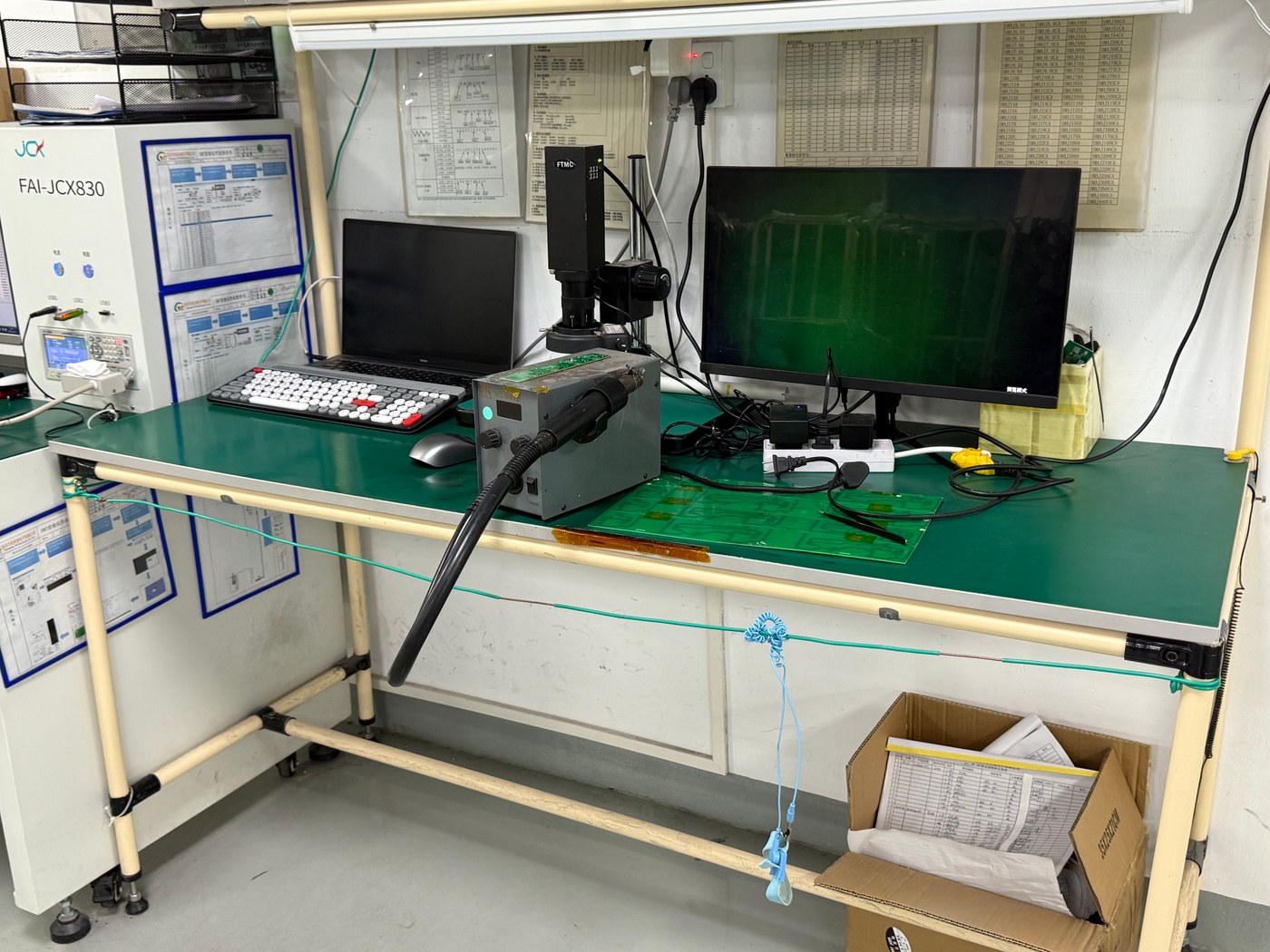Factory bench with an inspection camera, rework equipment, and an oscilloscope beside posted work instructions