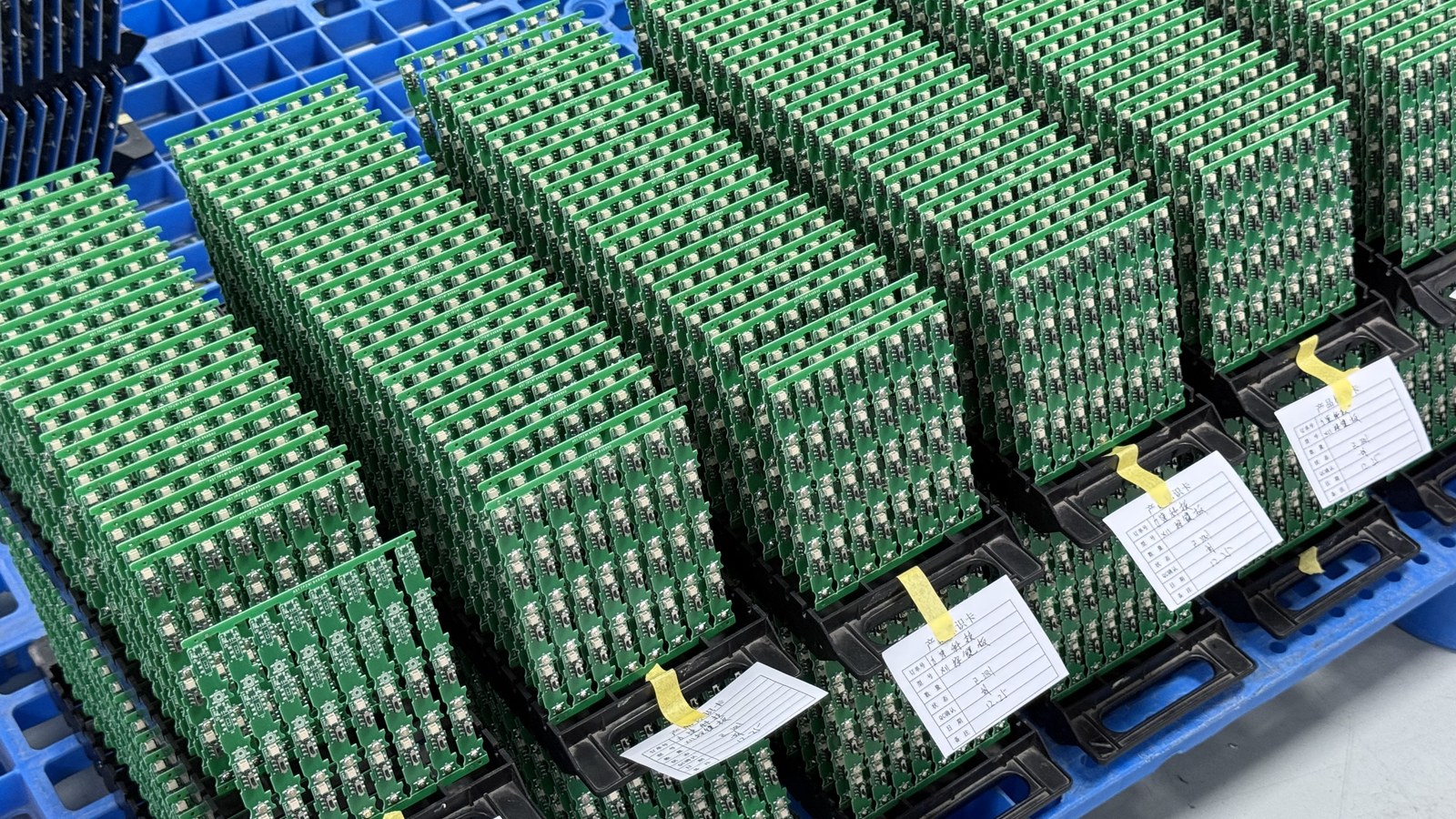 Assembled green circuit boards arranged vertically in factory carriers