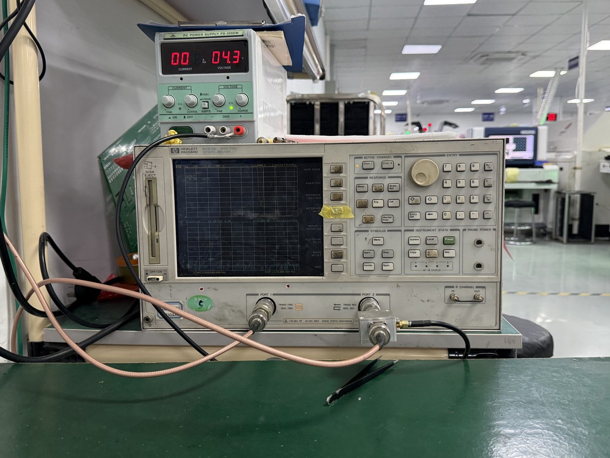 Factory bench with an HP network analyzer, connected coaxial leads and a DC power supply