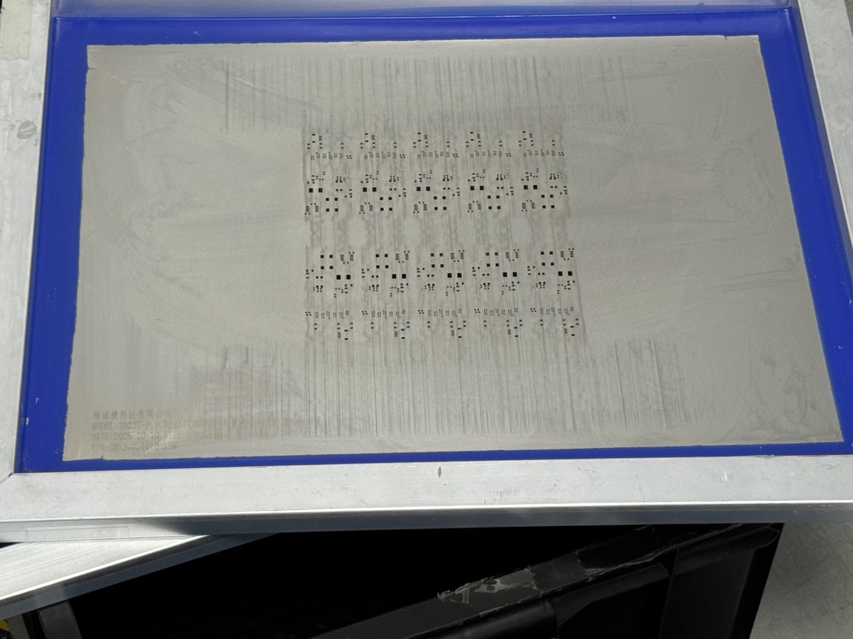 Factory solder-paste stencil in a blue frame with repeated component aperture patterns