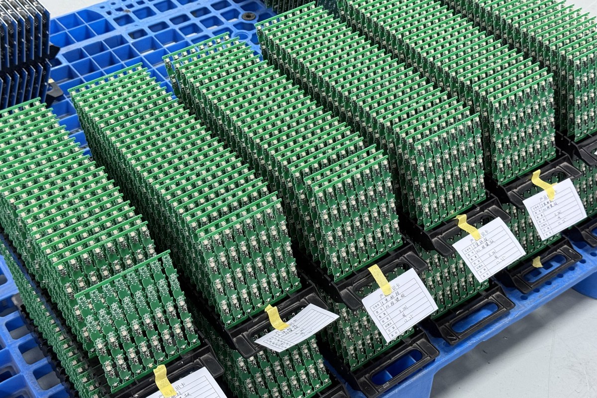 Real factory photo of multiple populated PCB assemblies held in production trays