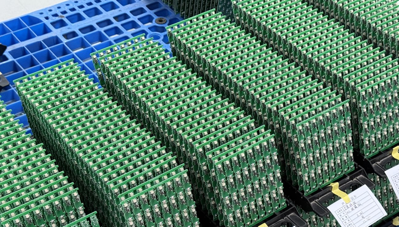 Real factory photo of assembled PCBs arranged in separate racks with paper batch tags