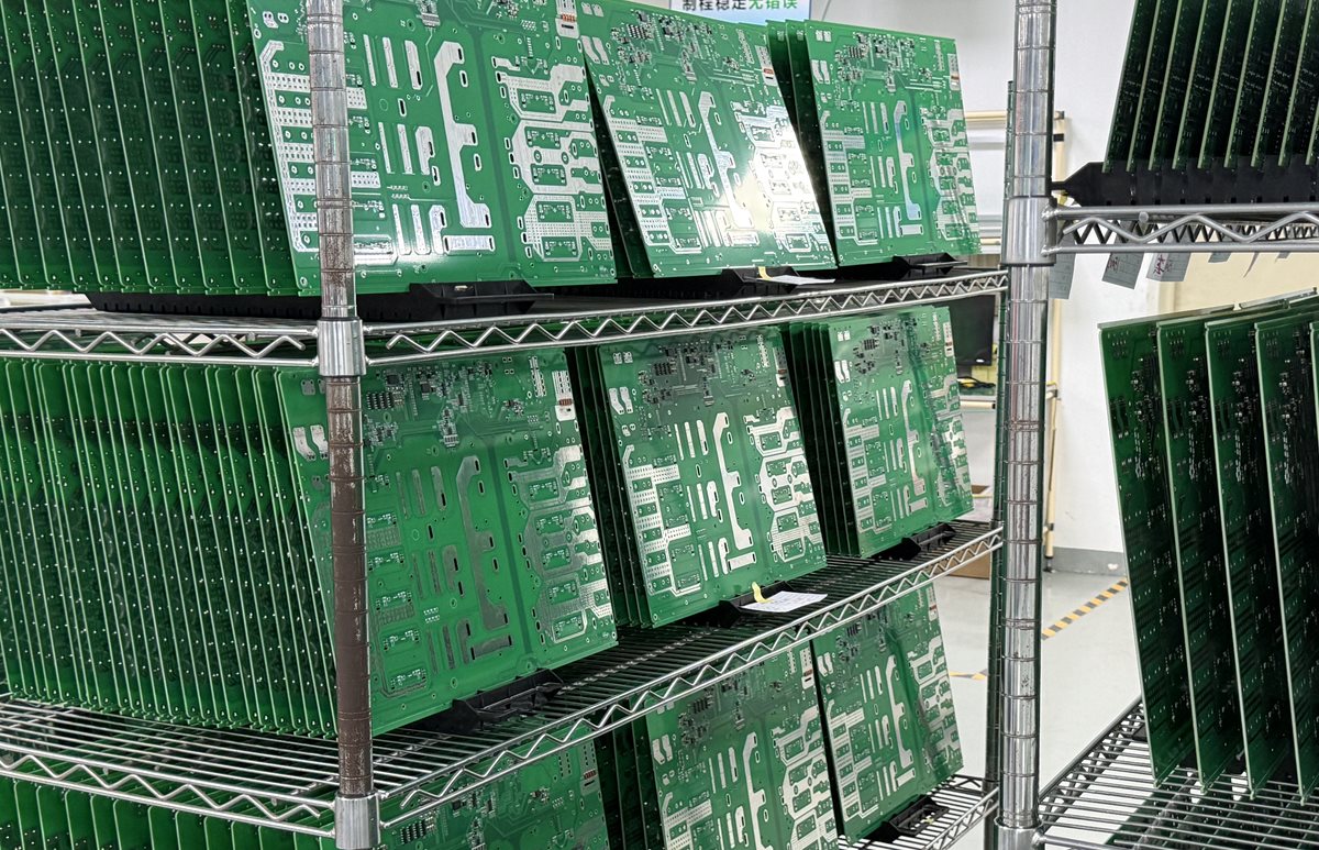 Green circuit boards held upright in separated slots on factory storage racks