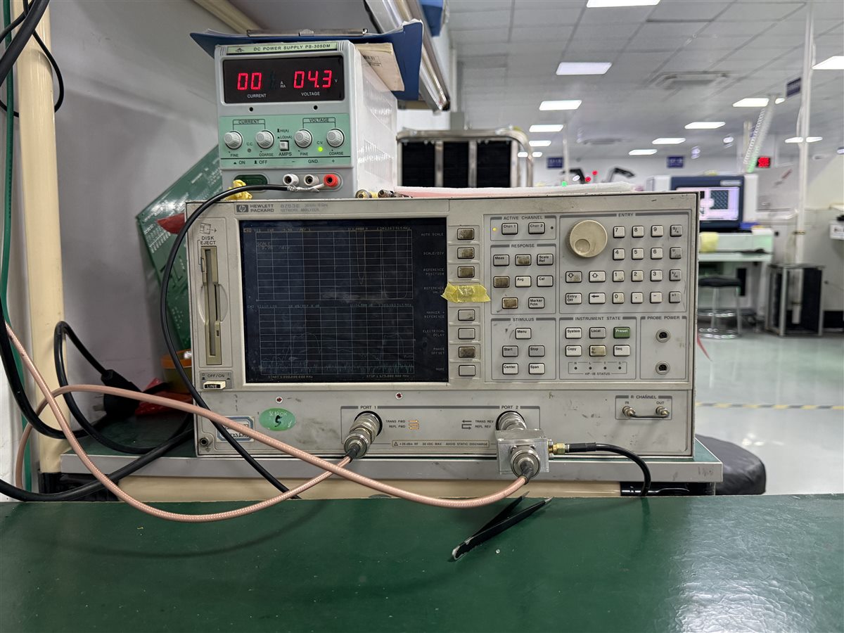 Real factory electrical bench instruments beside PCB work area, representing measurement planning for embedded passive boards